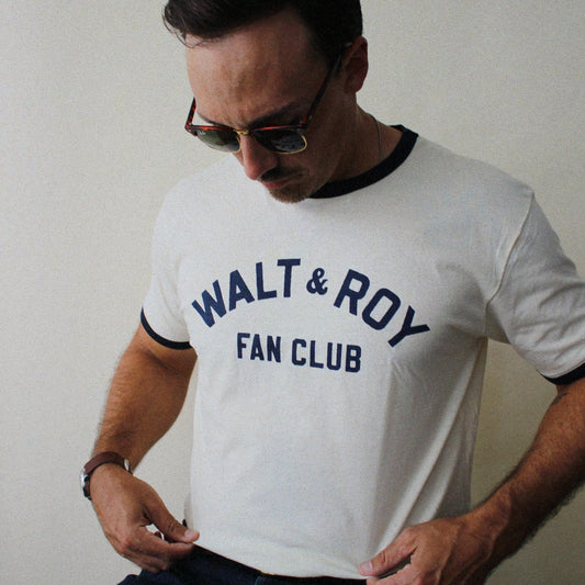 Man wearing a white t-shirt with 'Walt & Roy Fan Club' text against a plain background