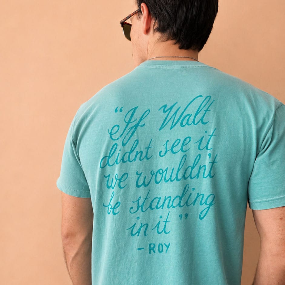 Back of the Florida Project seafoam green t-shirt with teal print that reads "If Walt didn't see it, we wouldn't be standing in it - Roy"