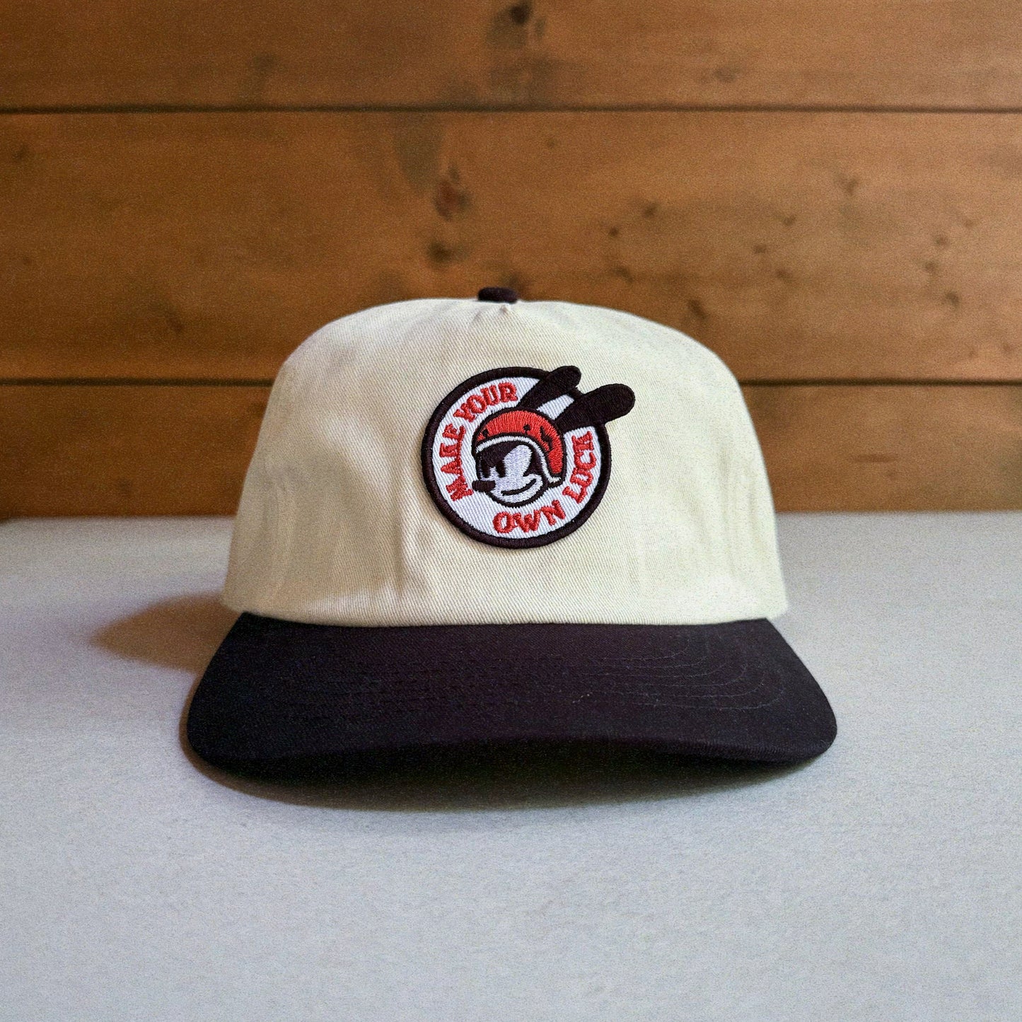 Two-tone natural and black cap with an embroidered patch featuring Oswald The Lucky Rabbit and the phrase 'Make Your Own Luck'