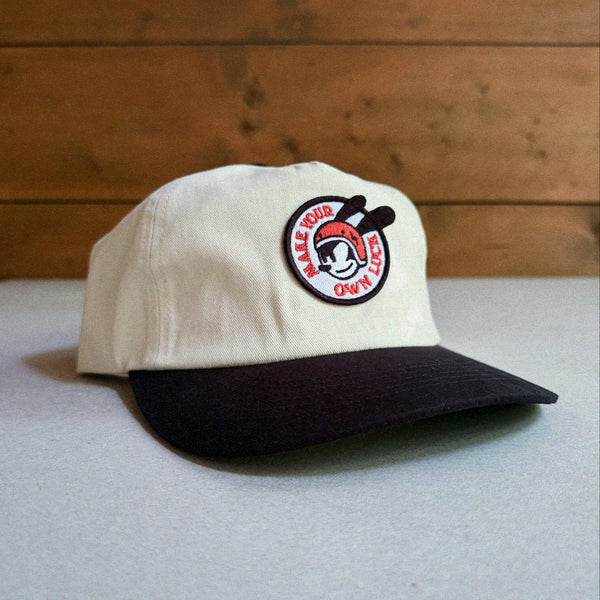 Two-tone natural and black cap with an embroidered patch featuring Oswald The Lucky Rabbit and the phrase 'Make Your Own Luck'
