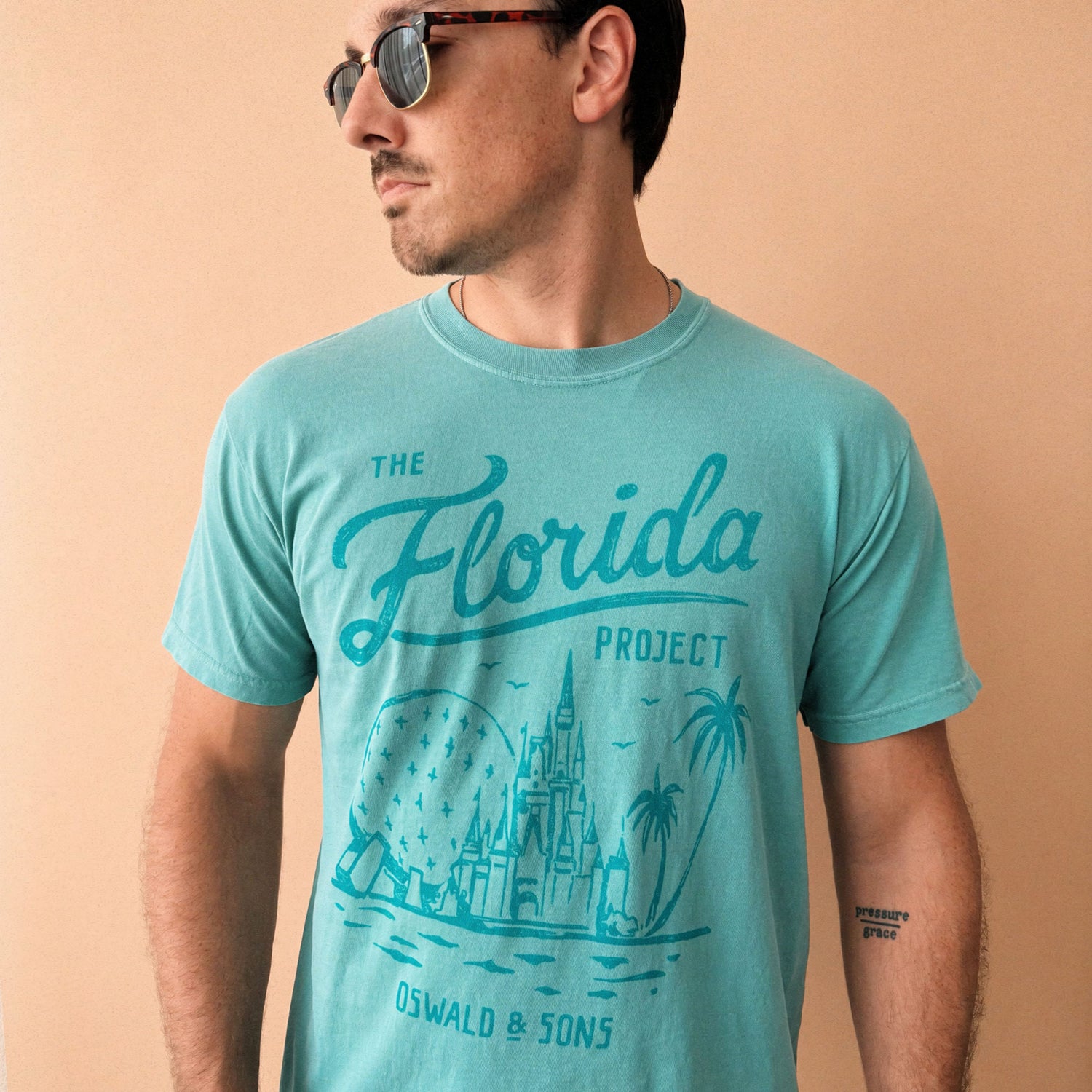 Front of the Florida Project seafoam green t-shirt with teal illustration of Epcot and the castle. Design reads The Florida Project