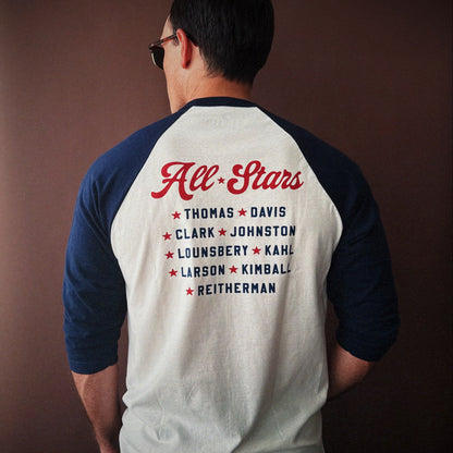 Person wearing The Nine Old Men baseball t-shirt with 'All Stars' and names printed on the back against a brown background