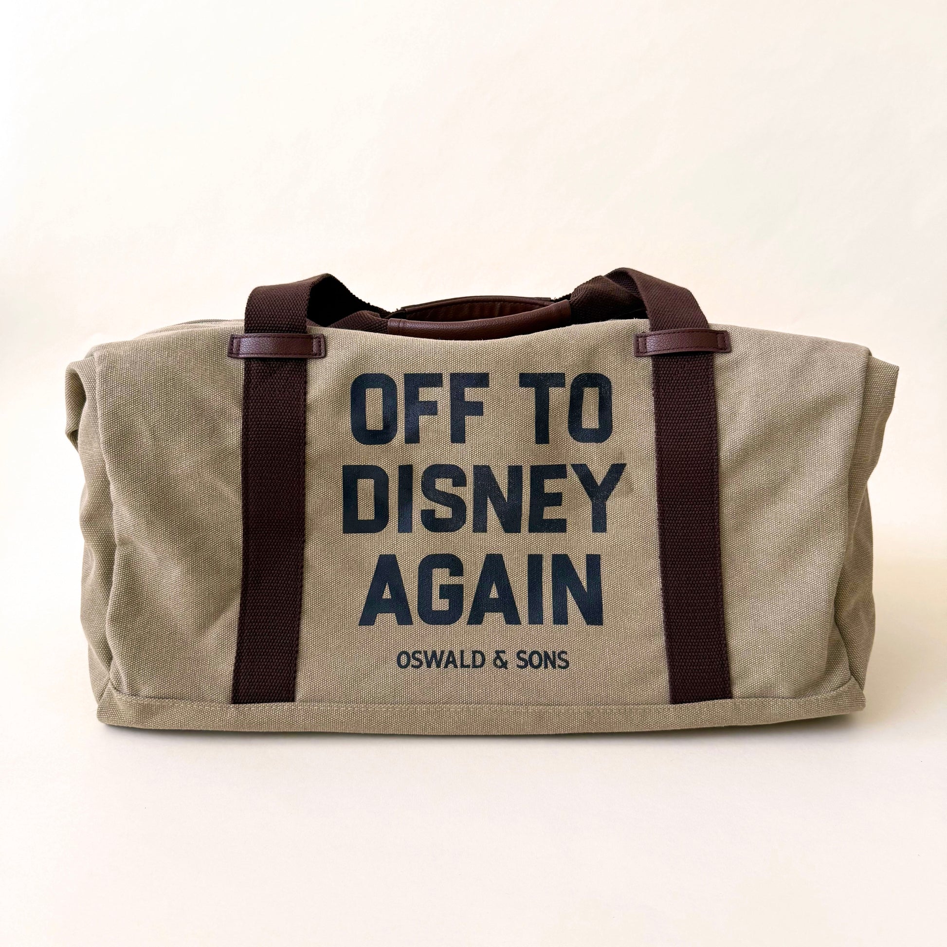Beige duffel bag with 'Off to Disney Again' text on a white background