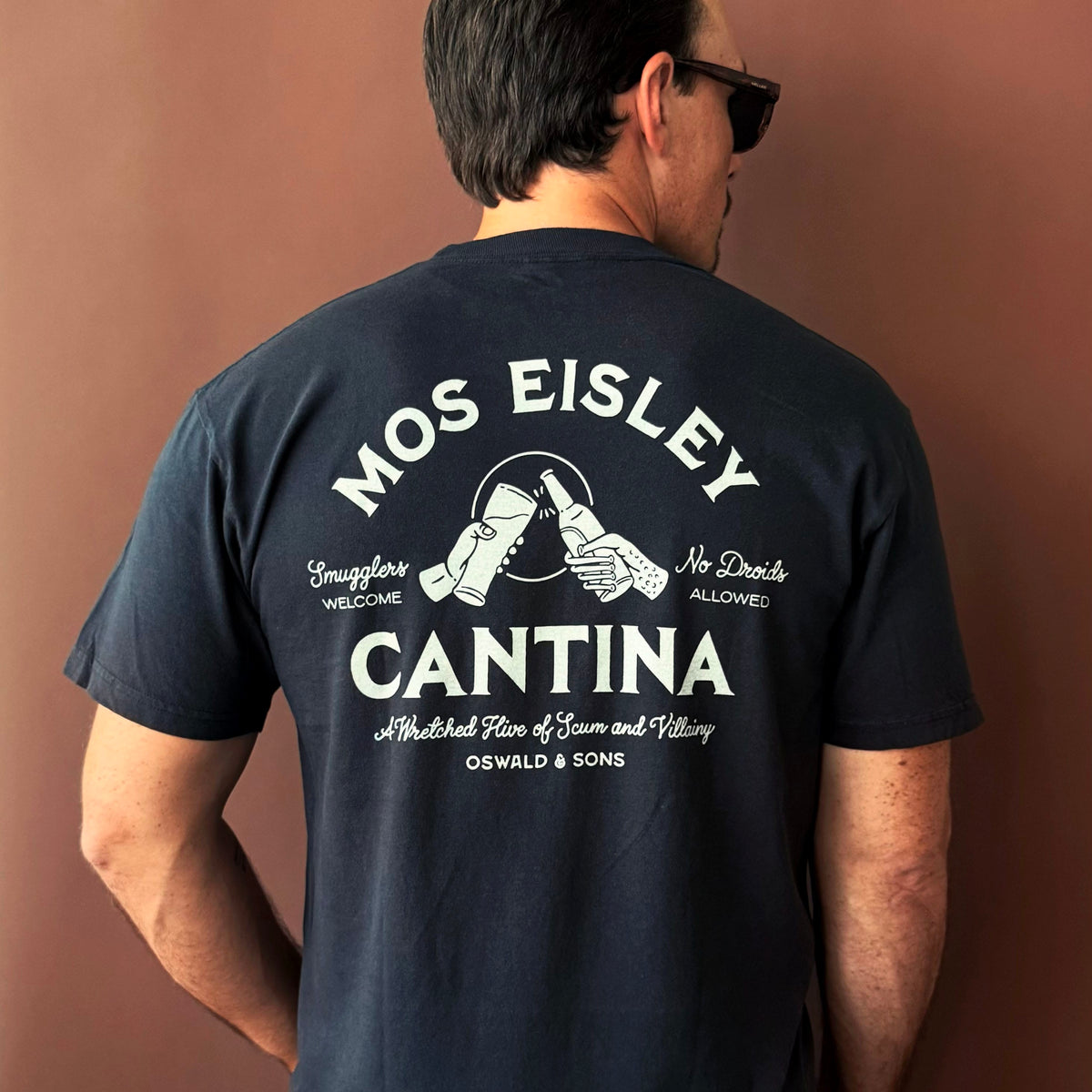 A man wearing a black Mos Eisley Cantina T-shirt from Oswald & Sons