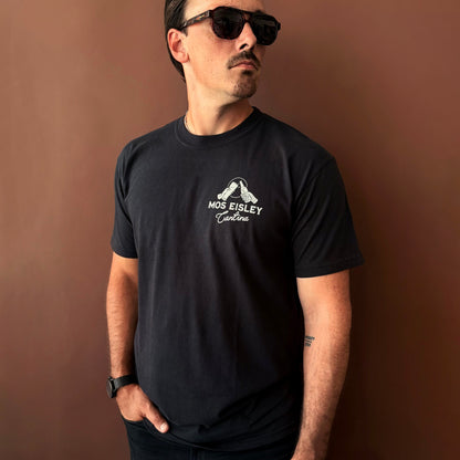 A man wearing a black Mos Eisley Cantina T-Shirt from Oswald & Sons